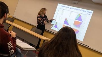 Data Science math class with professor gesturing at projected graphs